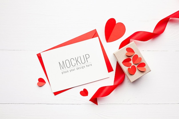 Valentijnsdag kaart mockup met geschenkdoos, rood lint en papieren harten