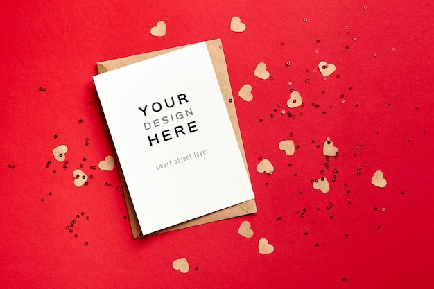 Valentijnsdag kaartmodel met envelop en kleine papieren harten op rood