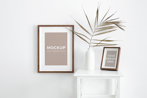 Verticale frames mockup op witte muur en meubels met droog palmblad in vaas