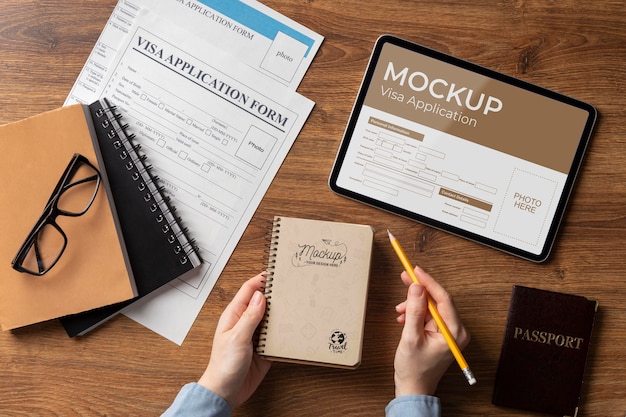 Visa application mock up in tablet on table with notebook holded by human hands, documents and passport