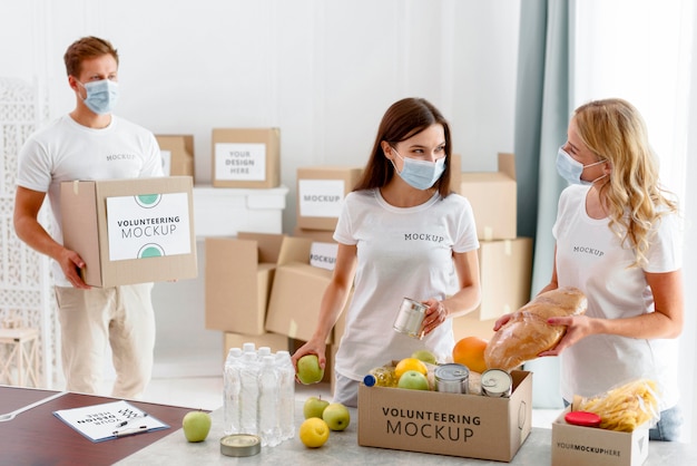 Volontari con maschere mediche che preparano scatole per la donazione