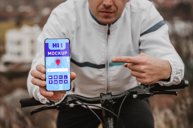 Vooraanzicht van mannelijke fietser wijzend op smartphone