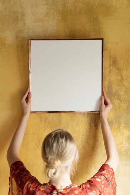 PSD vrouw die een framemodel op een gele grungemuur hangt