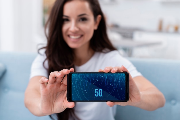 Vrouw die een telefoon met 5g-conceptmodel houden