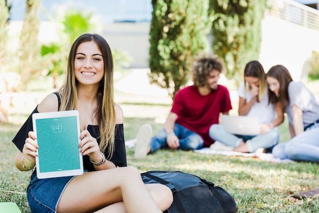 PSD vrouw die tabletmodel in park toont