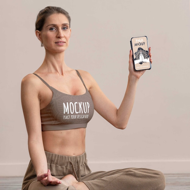 Vrouw doet yoga en houdt smartphone vast