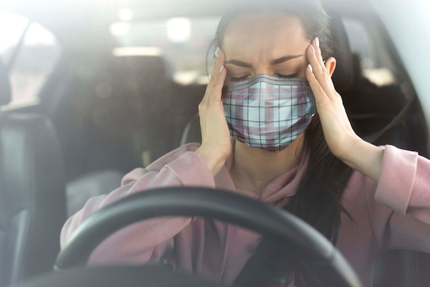 Vrouw in auto die hoofdpijn ervaart