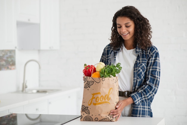 Vrouw in keuken met zak verse groenten