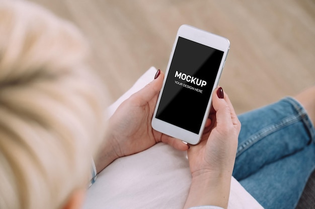 Vrouw met behulp van smartphone mockup zittend op de bank