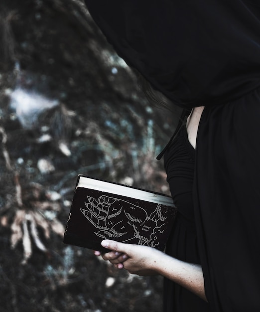 Vrouw met zwarte kaplezing van een spellboek