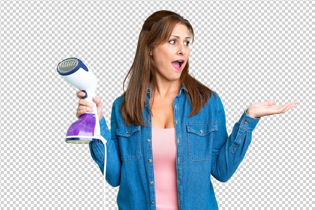 Vrouw van middelbare leeftijd met een ijzer over een geïsoleerde achtergrond met een verrassende gezichtsuitdrukking