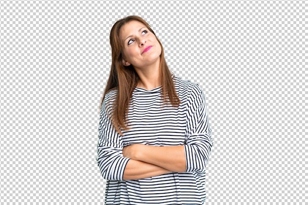 Vrouw van middelbare leeftijd over een geïsoleerde achtergrond die naar boven kijkt terwijl ze glimlacht