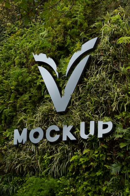 PSD design mock-up del logo della parete con sfondo di vegetazione