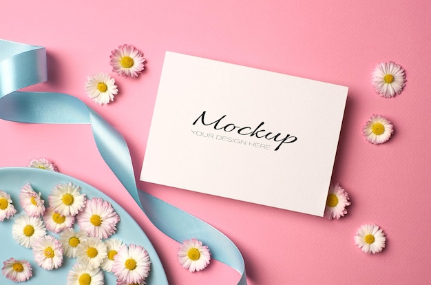 Wedding invitation card mockup with daisy flowers and ribbon on pink