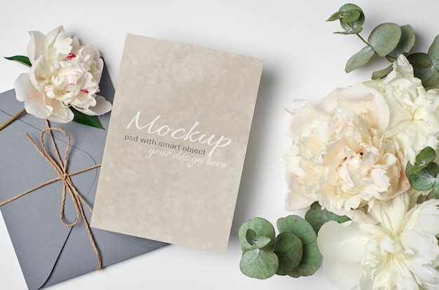 Wedding invitation or greeting card mockup with envelope and white peony flowers