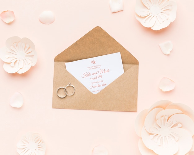 Wedding rings and invitation mock-up with paper flowers and petals