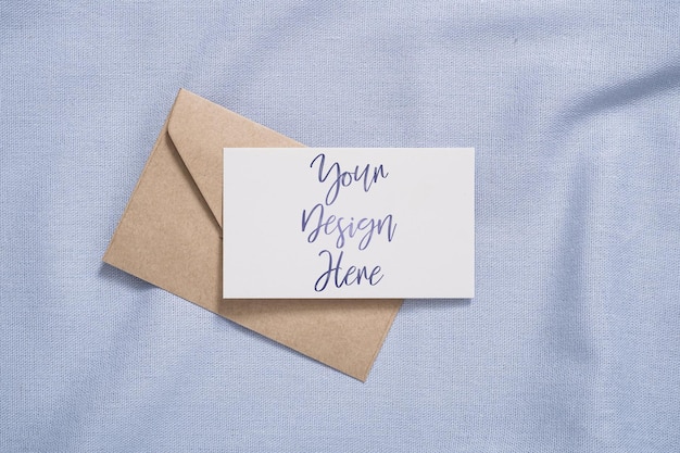White blank paper card and envelope mockup on blue colored textile