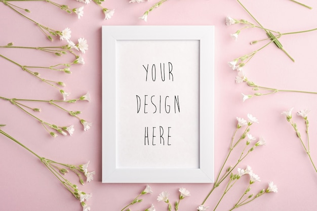 PSD white empty photo frame mockup with mouse-ear chickweed flowers on pink background, top view copy space