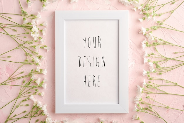 PSD white empty photo frame mockup with mouse-ear chickweed flowers on pink textured background, top view copy space