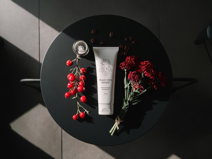 PSD white facewash tube on dark table next to to berries red flowers and coffee beans