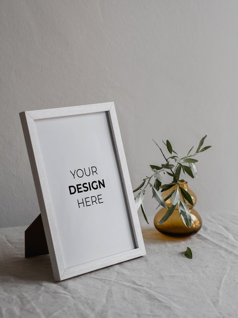 white picture frame mockup with vase and greenery on a linen table