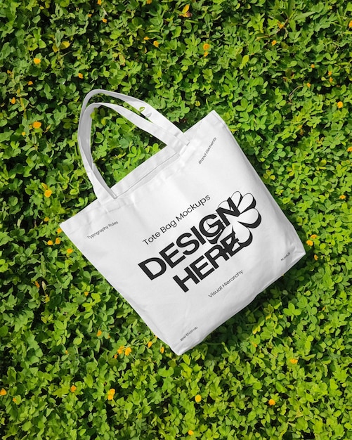 White tote bag mockup on a bed of green foliage
