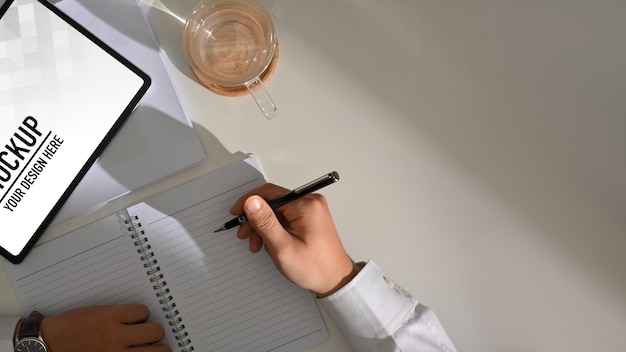 PSD widok z góry męskiej dłoni pisania na pustym notatniku podczas pracy z makietą cyfrowego tabletu