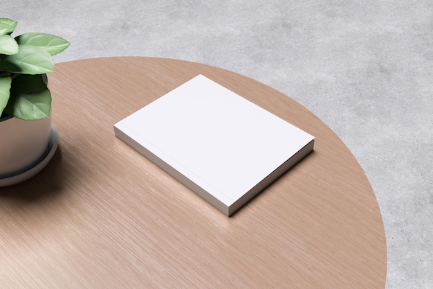 Wit boek op houten tafel met een plant en een betonnen achtergrond