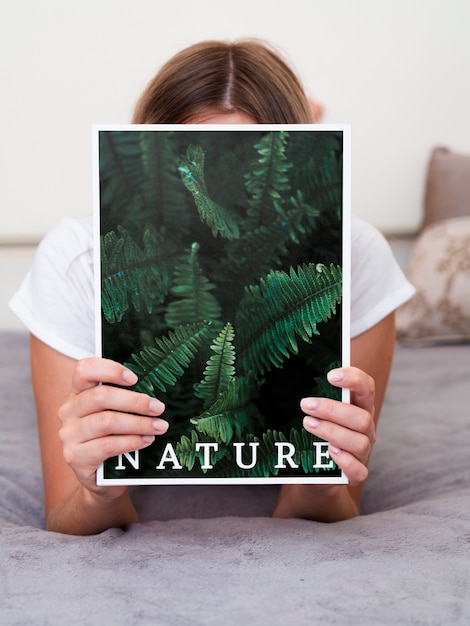 Donna a letto che tiene una rivista di natura