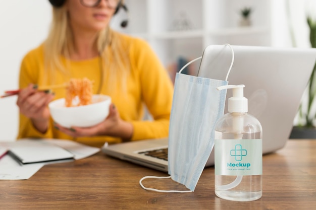 Woman eating at desk with disinfectant mock-up