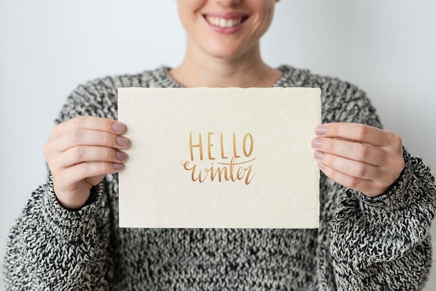 Woman in a gray sweater holding an earth tone card mockup