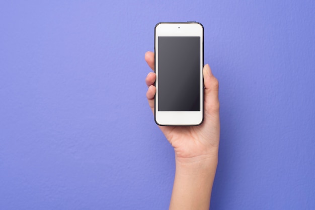 La mano della donna sta tenendo il modello del telefono su fondo porpora