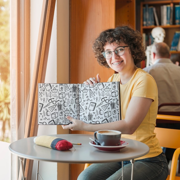 Woman holding book mockup in library