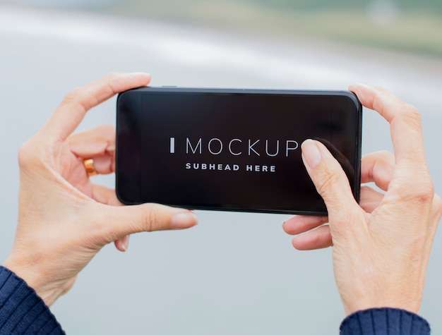 PSD woman holding a mobile phone mockup outdoors