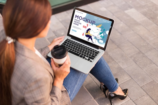 Woman holding a mock-up laptop outdoors