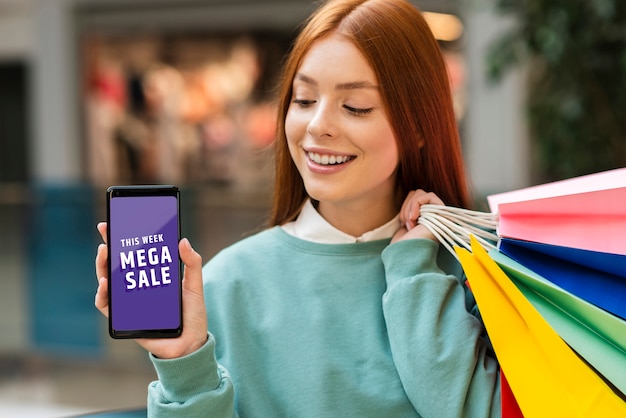 Woman holding paper bags and looking at her phone