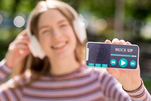 PSD woman holding phone with music app mock-up