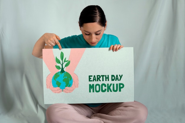 PSD woman holding signboard mock-up for earth day