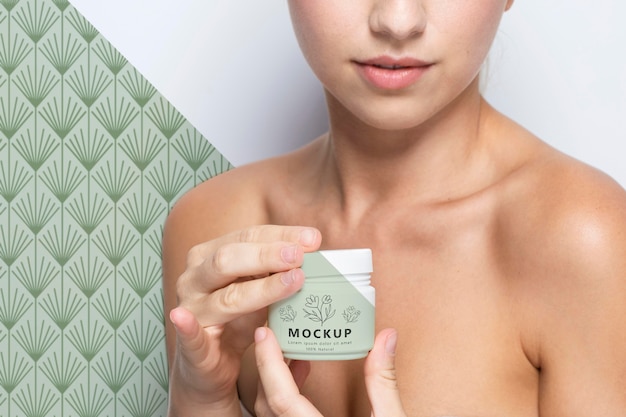 PSD woman holding a skincare product mock-up