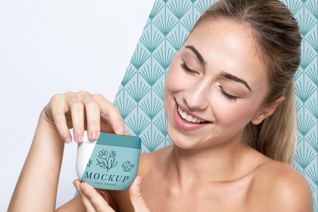 PSD woman holding a skincare product mock-up