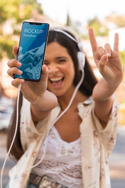 Woman holding smartphone and listening to music on headphones