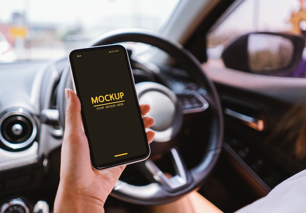 PSD woman holding smartphone mockup in the car