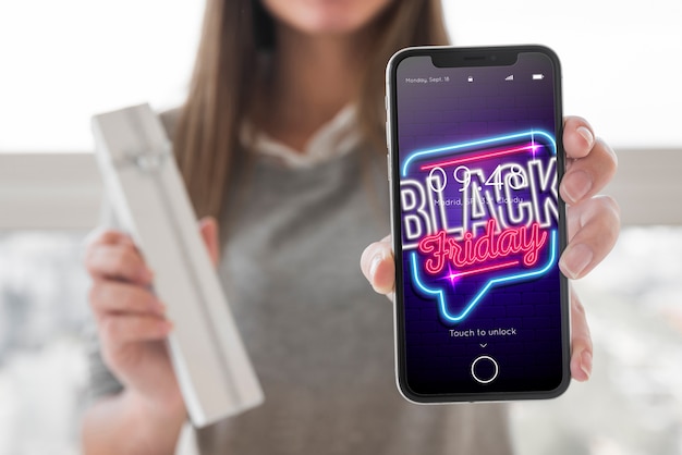 Modello dello smartphone della tenuta della donna con il concetto di venerdì nero