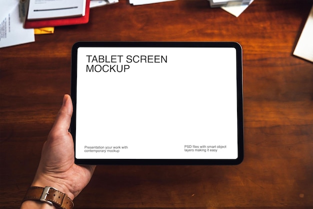 a woman holding a tablet on a wooden table