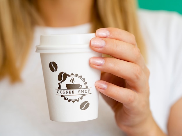 Woman holding up a coffee paper cup mock-up