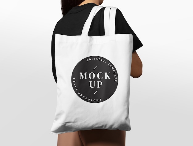 Una donna sta portando una borsa tote che dice mock up.