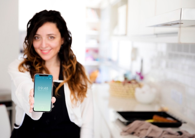 PSD donna in cucina che presenta smartphone mockup