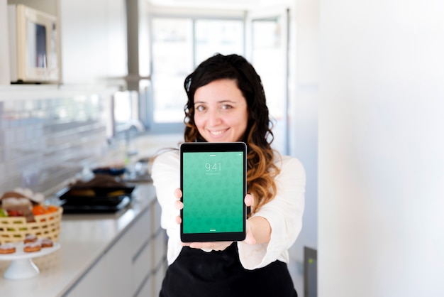 Woman in kitchen presenting tablet mockup