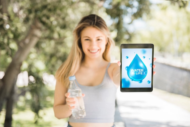 PSD woman presenting tablet mockup with water concept