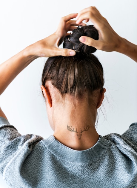 woman putting her hair up in a bun